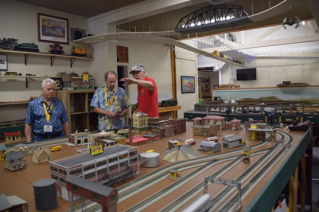 Three men look at a model train set